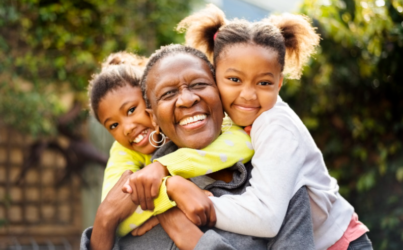 An older family member and two children hugging and smiling